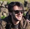 Samuel smiling, wearing sunglasses on a sunny day in Porto